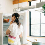 冷蔵庫を見つめる女性イメージ